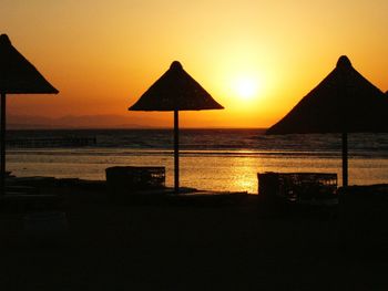 Silhouette beach against clear sky during sunset