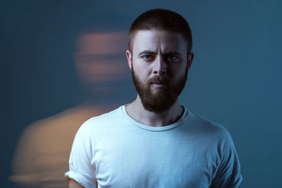 Portrait of young man standing against black background