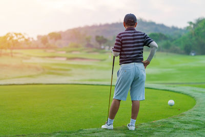 Rear view of woman standing on golf course