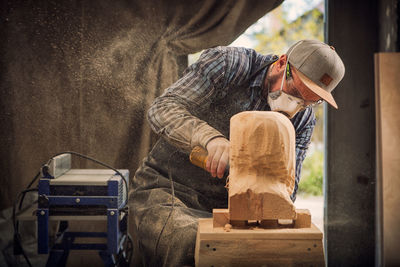 Experienced carpenter in work clothes saws a man's head with a tree , using an angle grinder 