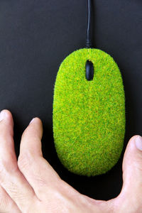 Close-up of man holding leaf over black background