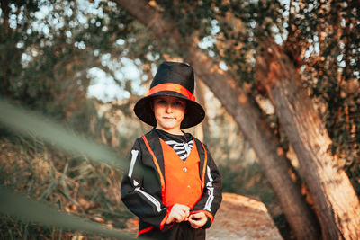 Portrait of boy standing against trees