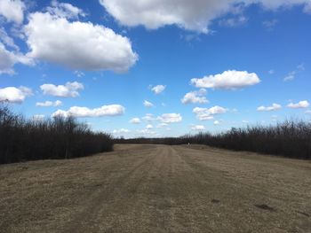 Road amidst field against sky