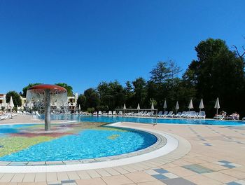 Fountain in swimming pool against clear blue sky