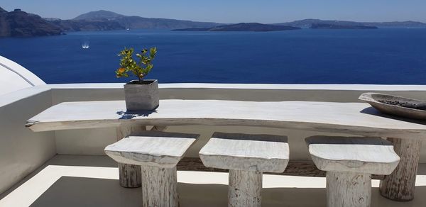 Chairs and table by sea against sky