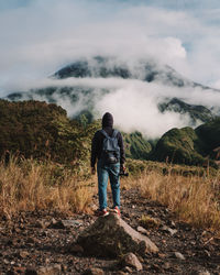 Rear view of man standing on mountain against sky