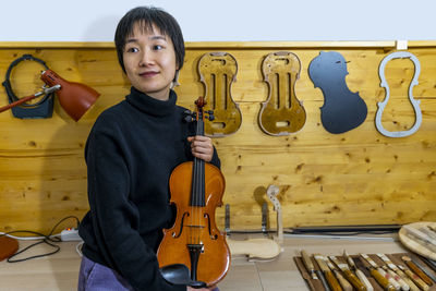 Young chinese violin maker at work in her workshop