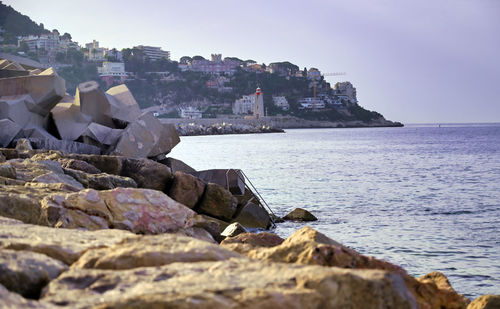 Rocks on beach by sea against sky