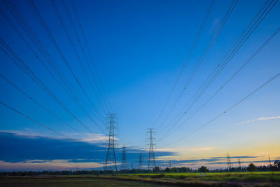 Low angle view of electricity pylon on field against sky