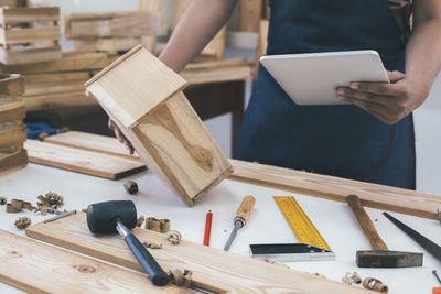 Midsection of carpenter using digital tablet in workshop