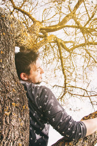 Portrait of boy standing on tree trunk