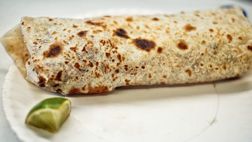 Close-up of fresh burrito with lemon piece served in plate