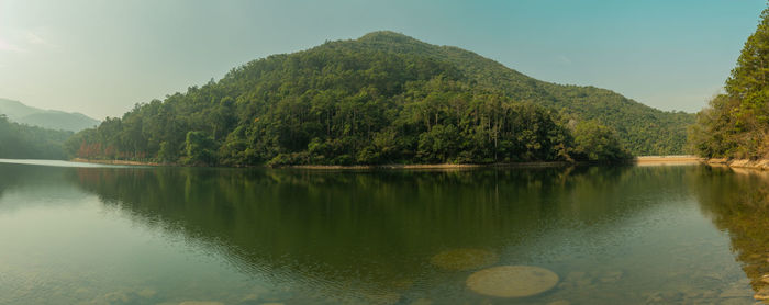 Scenic view of lake by trees against sky