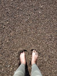 Low section of person standing on sand