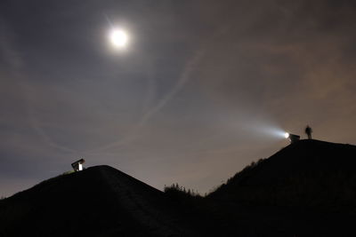 Low angle view of silhouette person against moon in sky