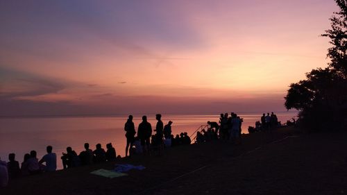 Silhouette people at beach against sky during sunset