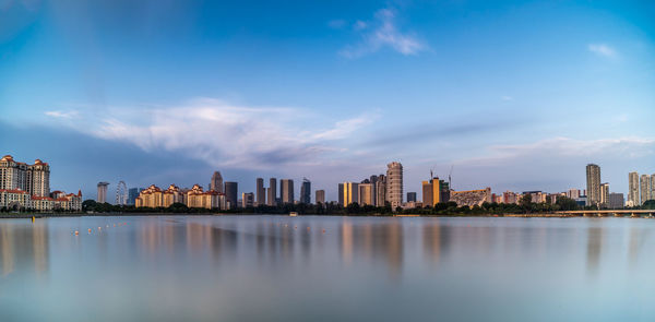 City at waterfront against cloudy sky