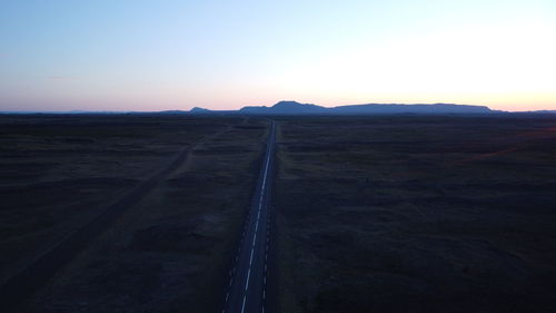 Scenic view of land against clear sky during sunset