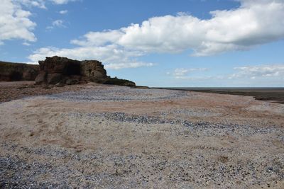 Rock formations on beach against sky