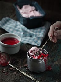 Cropped hand of woman having dessert in container on table