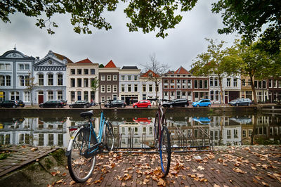 Bicycle by canal against buildings in city