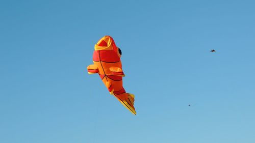 Low angle view of kite flying against clear blue sky