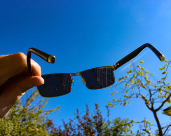 Low angle view of person hand against clear blue sky