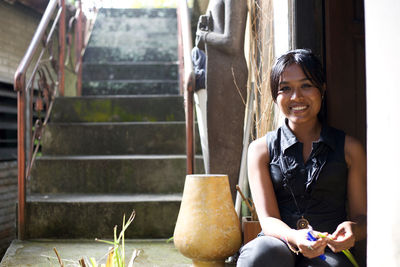 Portrait of smiling young woman sitting on staircase