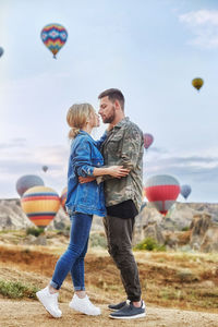 Couple in love stands on background of balloons in cappadocia. man and woman on hill look 