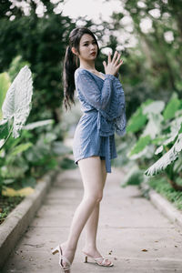 Portrait of young woman standing against plants