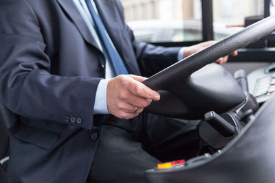 Midsection of man using mobile phone in bus