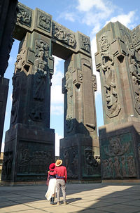 Couple looking up to the 30 meter tall massive pillars of the chronicle of georgia, tbilisi, georgia