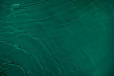 Transparent dark green colored clear calm water surface texture