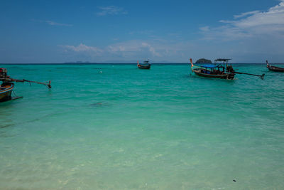 Boats in sea against blue sky