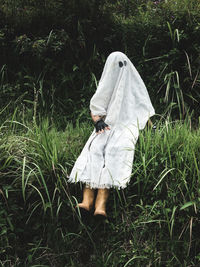 Person disguised as ghost for halloween in green grass field