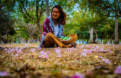 Portrait of smiling young woman sitting on plant