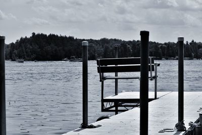 Wooden posts in lake against sky