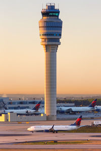 Airplane on airport runway against sky during sunset