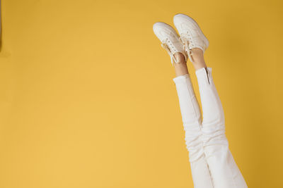 Cropped hand of man holding key against yellow background