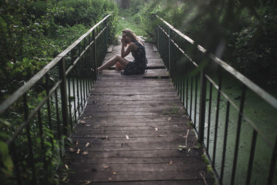 Woman sitting on the floor of a wooden bridge