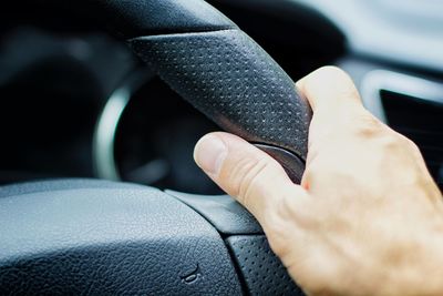 Cropped hand holding car steering wheel