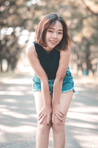 Portrait of smiling young woman bending on road 