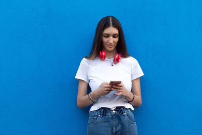 Beautiful young woman standing against blue wall