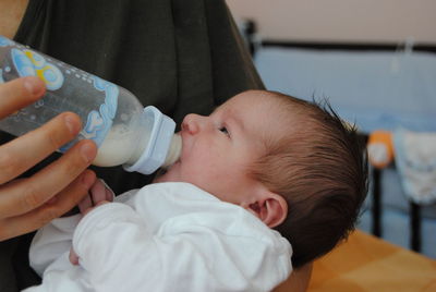 Midsection of mother feeding baby at home