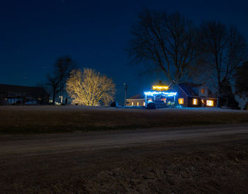 Illuminated street lights on road in city at night