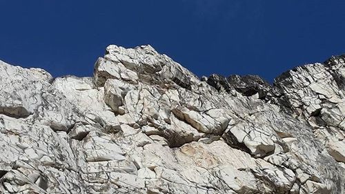 Low angle view of rock formation against clear blue sky