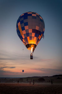 Hot air balloon flying over land during sunset