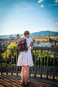 Rear view of woman standing by railing against sky