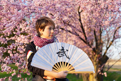 Young caucasian woman posing a wushu martial art posture in a sunny day, a pink tree in background