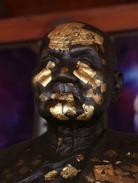 Close-up of human sculpture with gold leaf on it